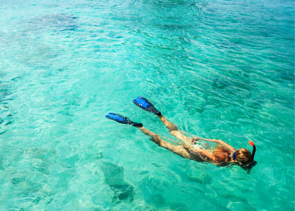 A woman snorkeling and shore diving in the clear blue water at Malcolm’s Road Beach.