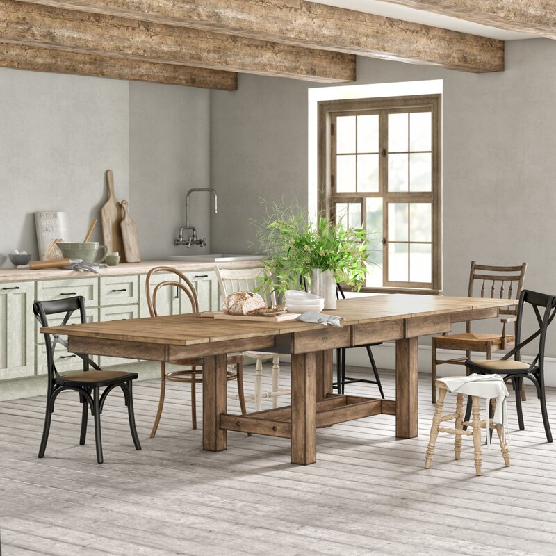 A wooden table set in a rustic kitchen with exposed wood beams 