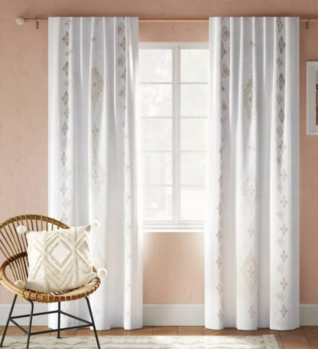 White drapes and boho wicket chair with white pillow