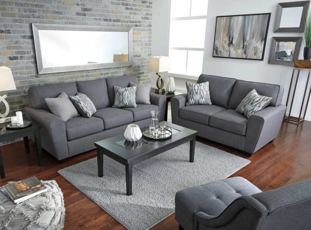 A grey sofa and love seat set with matching chair and rug