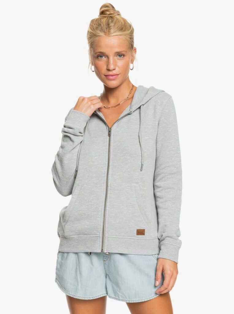 Young woman with blonde hair wears a grey zip up hoodie with cloth shorts from Roxy