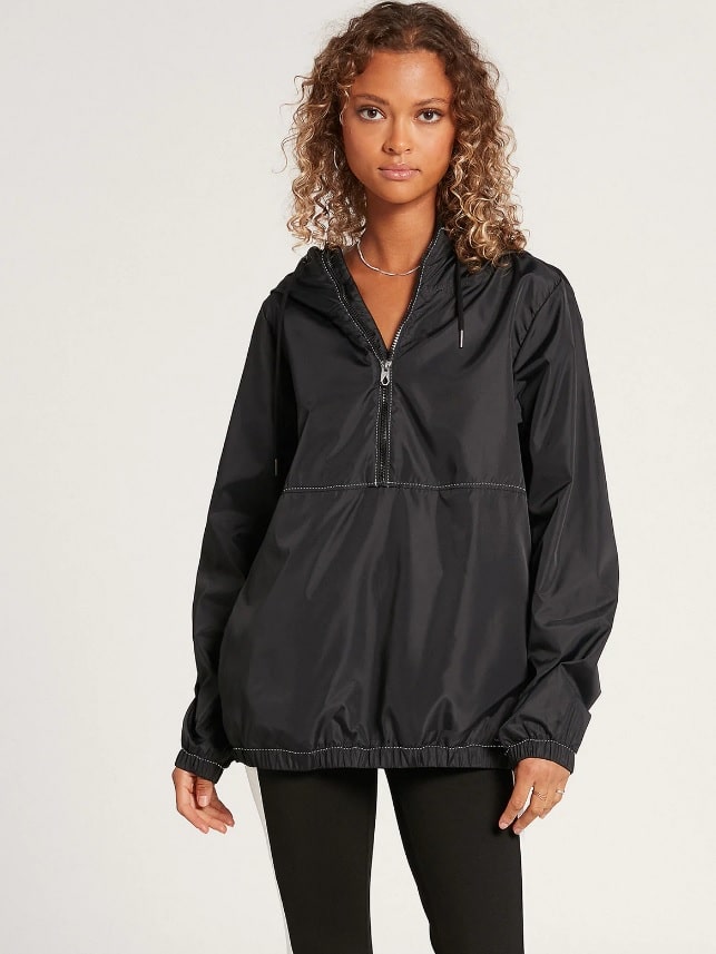 Young woman with curly hair wears Volcom's WIND IT UP JACKET - BLACK with black pants