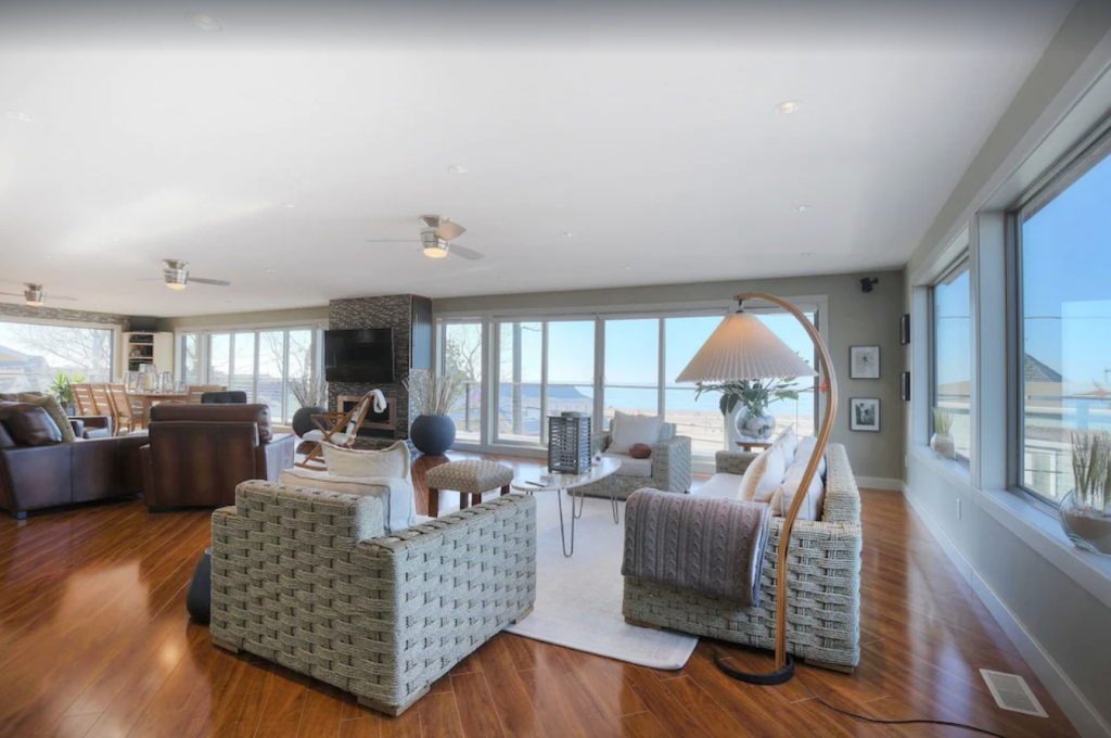 A living room with hardwood floors and a view of the ocean - 3-story Luxury Beach Front Home Close to North Beach in South Haven.