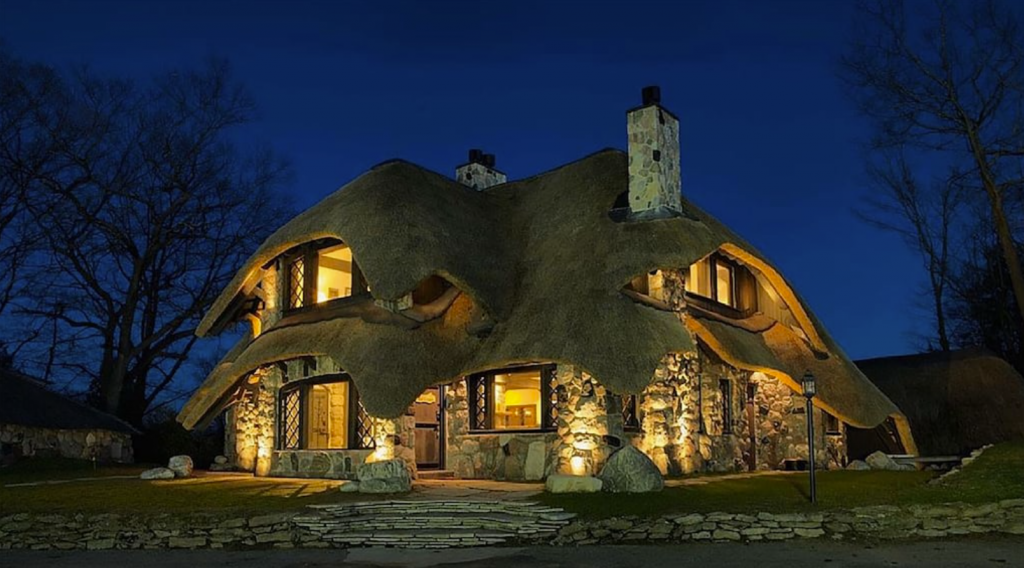 A house with a thatched roof lit up at night - Charlevoix Mushroom Thatch House in Charlevoix, Michigan.