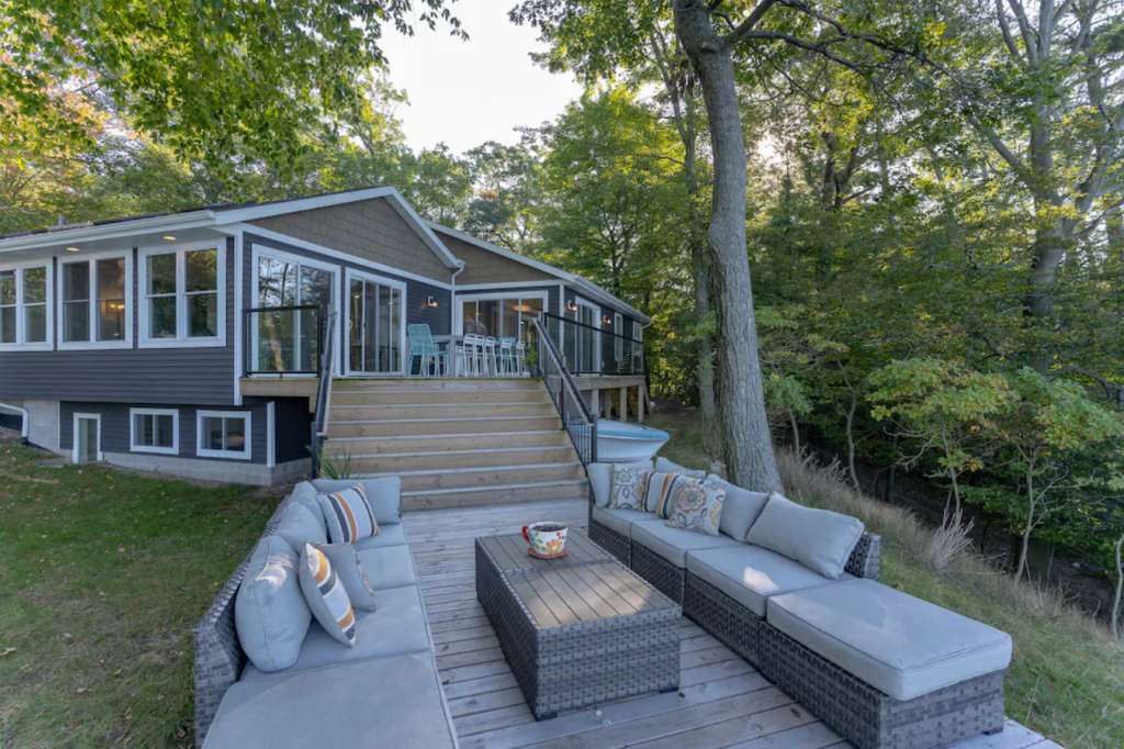 A deck with couches and chairs on the side of a house - Luxury 6-bedroom Cottage with Direct Lake Michigan Access in Muskegon, MI.