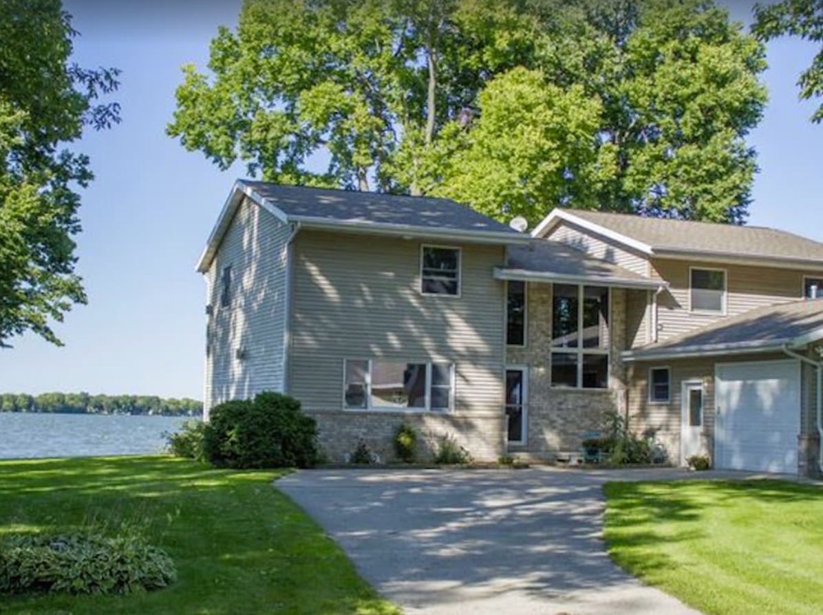 An exterior image of a quaint two-story home with a tan siding and brick exterior. The home overlooks Lake Winnebago in Neenah, Wisconsin.