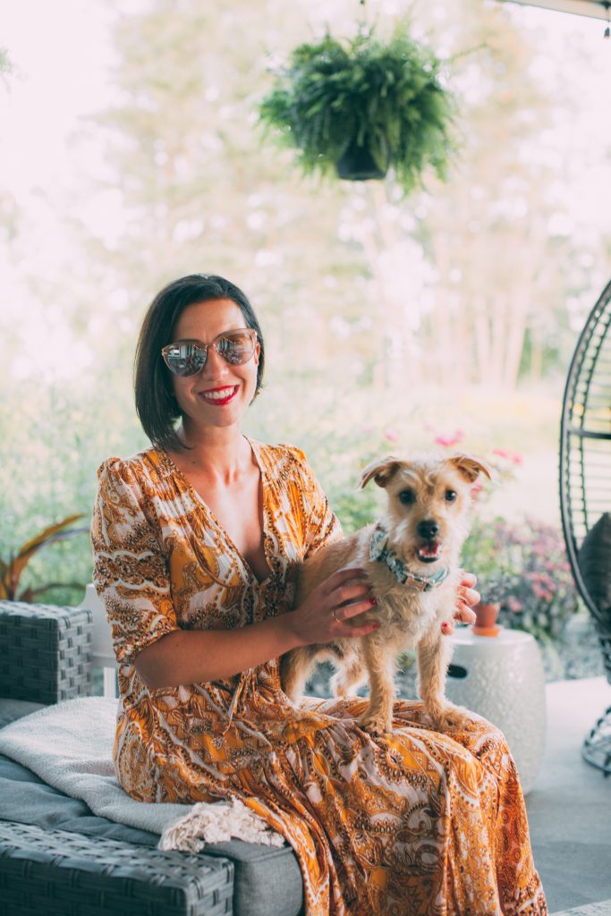 Lindsey of Have Clothes, Will Travel holding her puppy, Buddy, while wearing a yellow Salty Crush maxi dress
