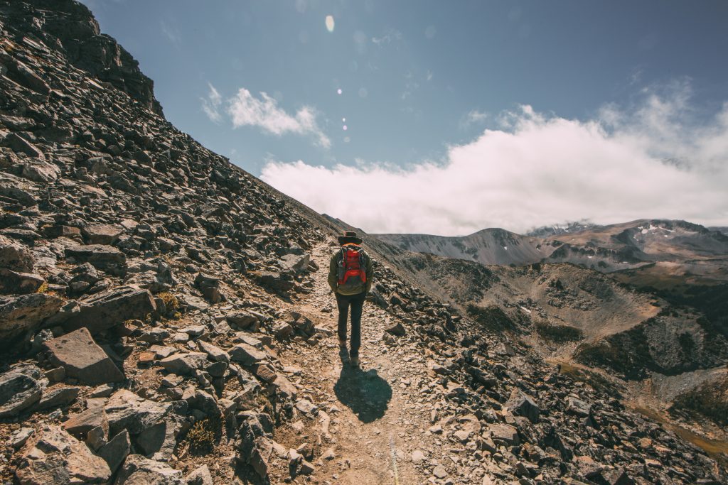 Zac hiking with an orange backpack on a very rock trail on the Mount Fremont Fire Lookout