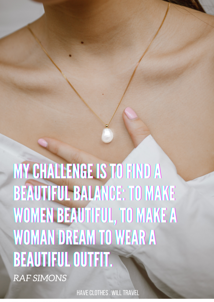 An image shows a woman's bust and collarbones. She's wearing a simple gold chain necklace with a single pearl pendant, and an off-the-shoulder white collared shirt. White text over the image reads, "My challenge is to find a beautiful balance: to make women beautiful, to make a woman dream to wear a beautiful outfit. - Raf Simons"