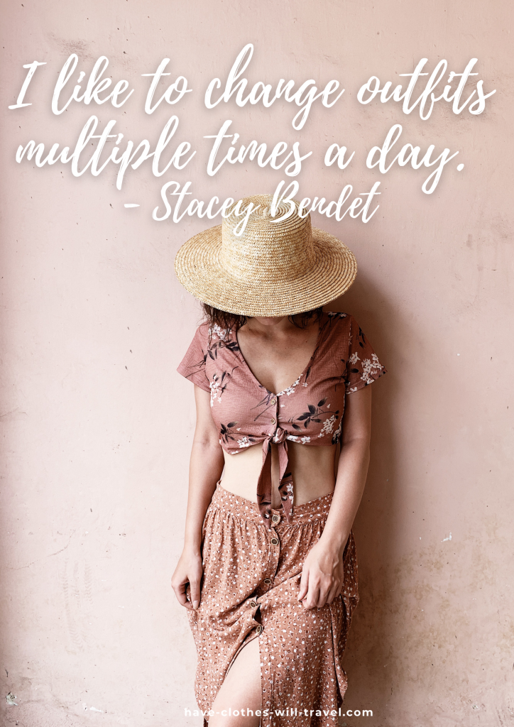 A young woman stands against a light pink wall. A straw hat covered her face. She's wearing a cropped pink floral shirt and knee-length floral patterned skirt with a thigh-high slit. White text on the image reads, "I like to change outfits multiple times a day. - Stacey Bendet"