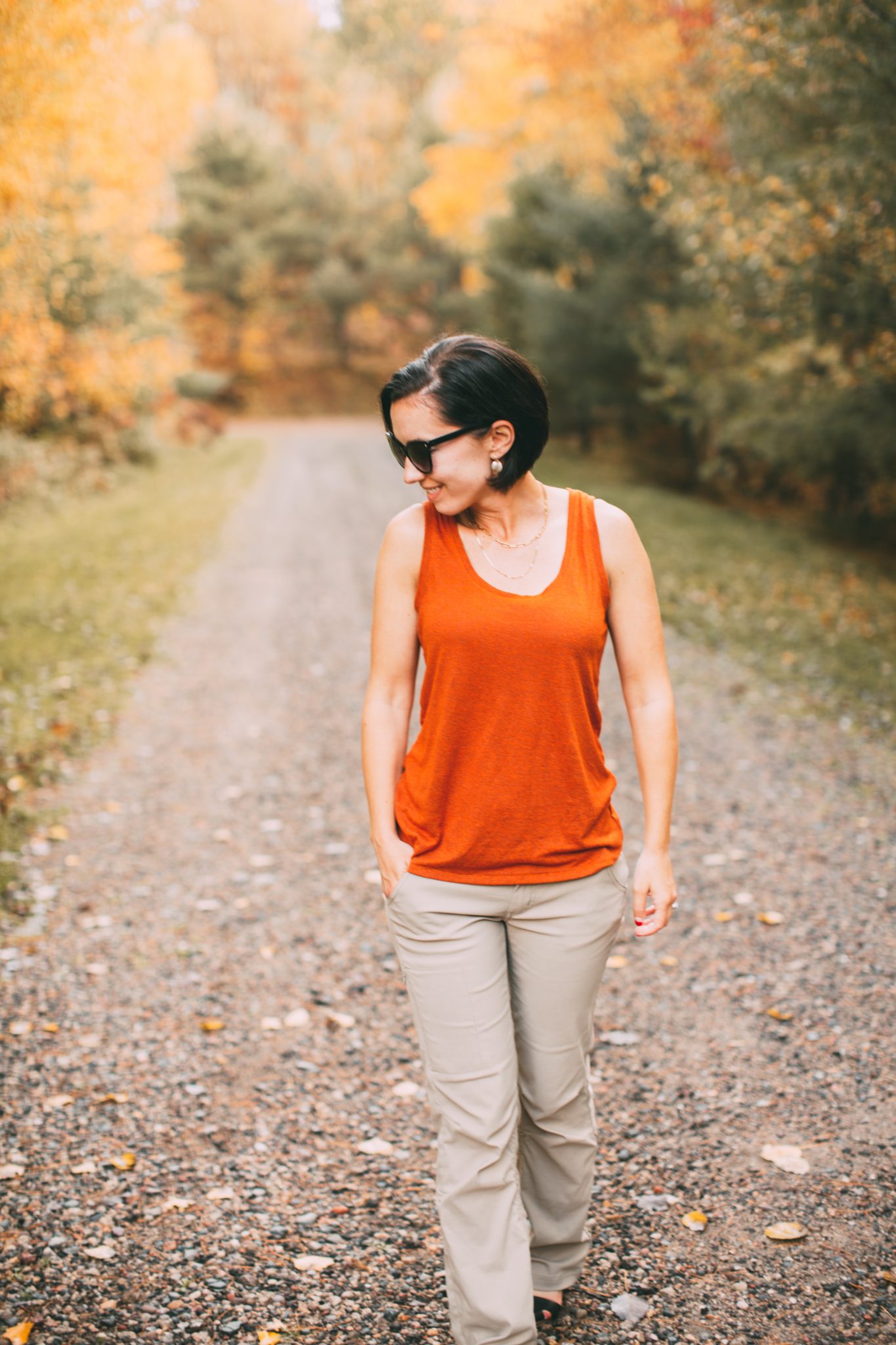 I'm wearing an orange prAna tank top & khaki pants here and am walking on a gravel road surrounded by fall foliage