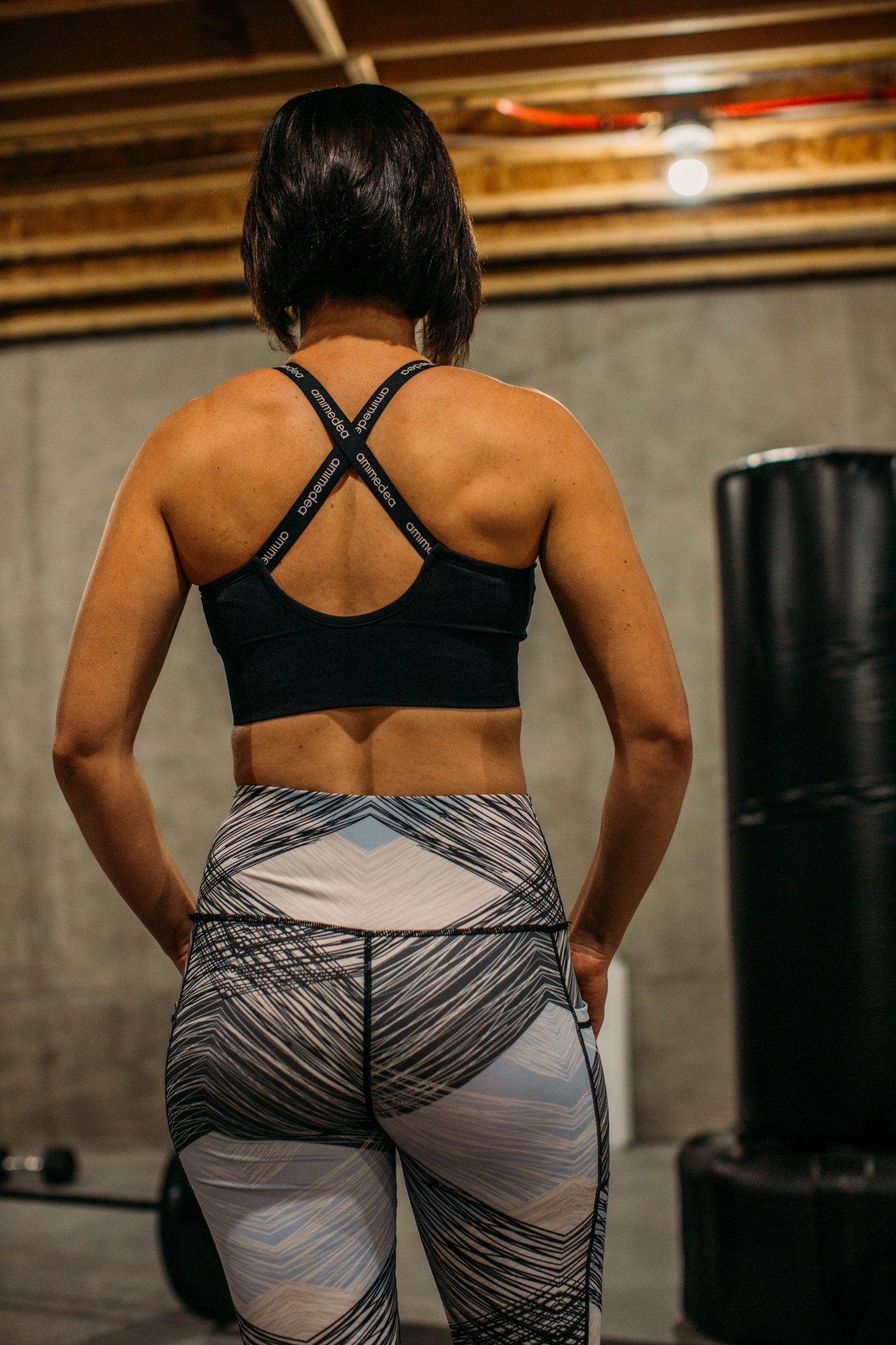 Back of a woman wearing a zipper front crisscross sports bra in black from Chicwish.