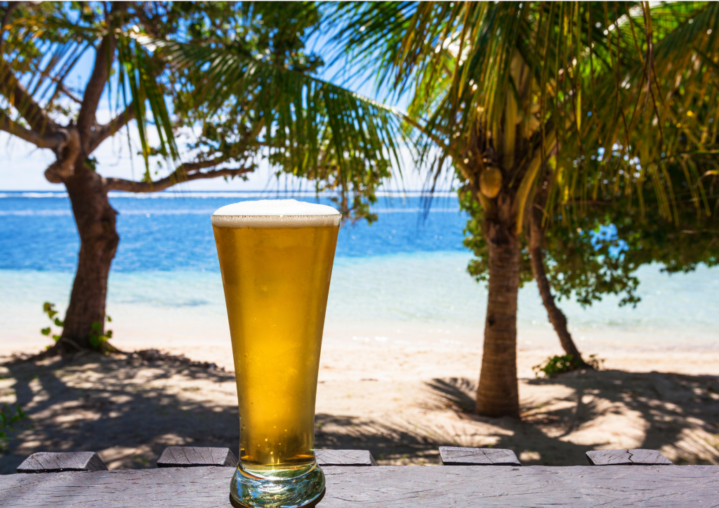 A glass of beer on a table in front of a beach in Grand Turk.