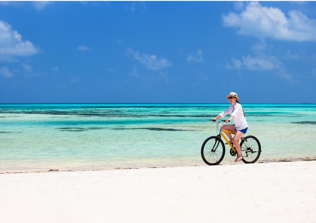 A woman riding a bicycle on a beach in Grand Turk.