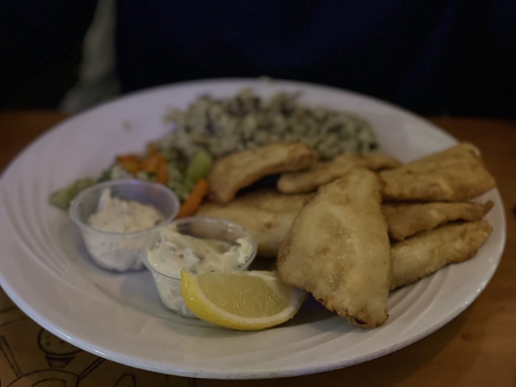 A classic Wisconsin fish fry - pieces of deep-fried fish served with lemon and tartar sauce and sides of vegetables.