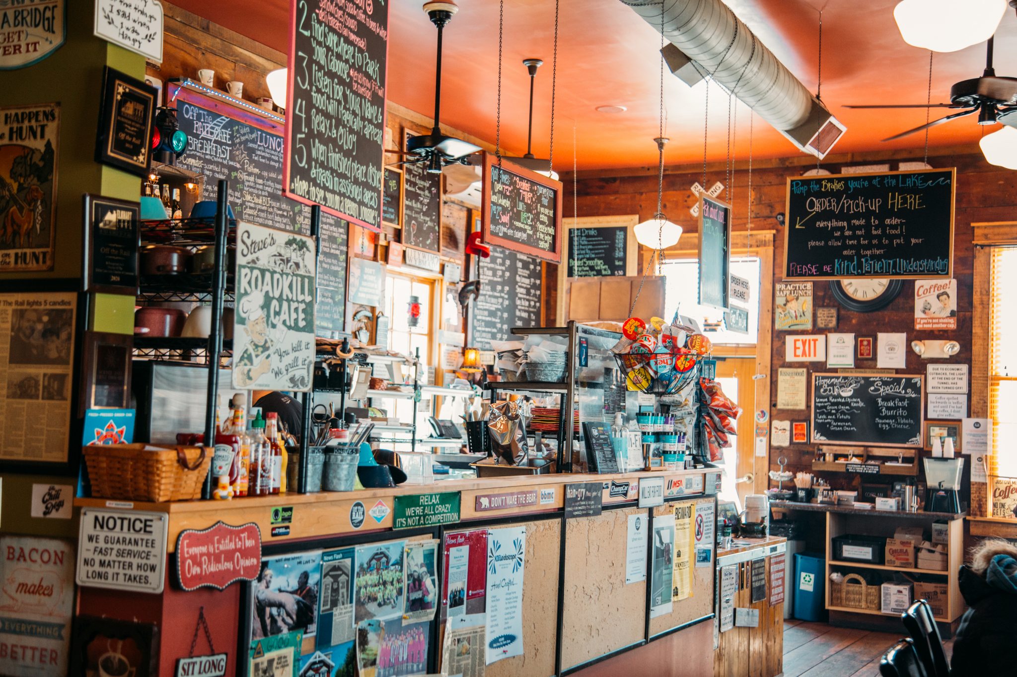 The inside of Off The Rail in Elkhart Lake is a small cafe with walls and counters covered in colorful signage and flyers.