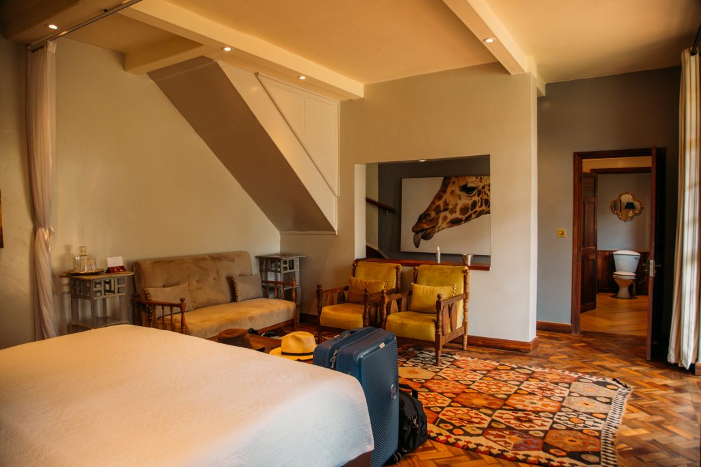A hotel bedroom with a giraffe on the wall.