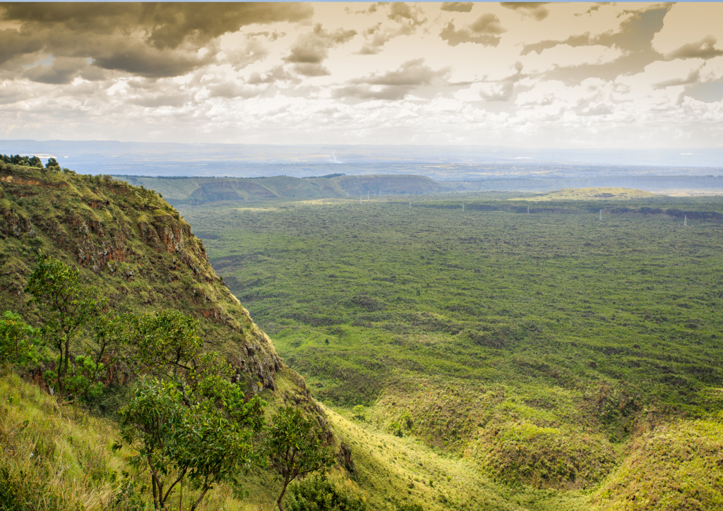 A view of a hillside with trees and a cloudy sky near Menengai Crater.
