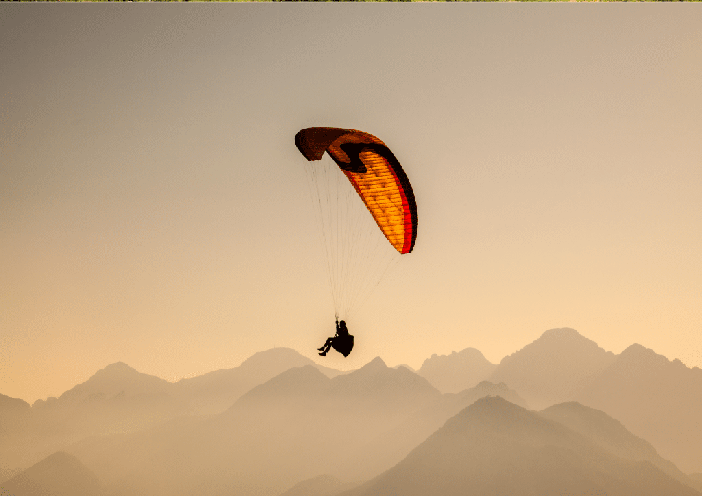 A person is paragliding over a mountain range in Kerio Valley.