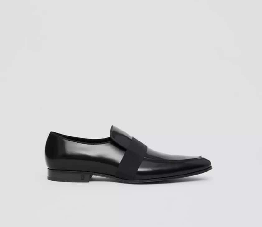 A black leather loafer with a buckle on the side.