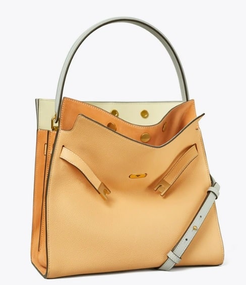 This Tory Burch bag is crafted from smooth caramel and cream colored suede leather and features a "double" look with multiple pockets and straps.