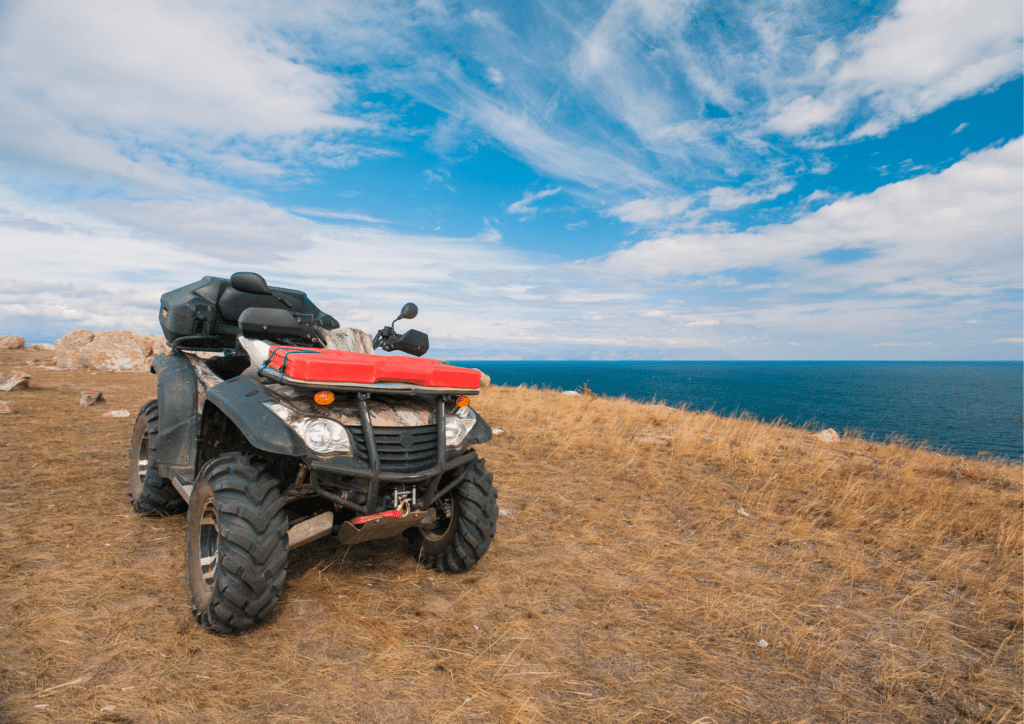 An ATV sits on the side of a cliff overlooking the ocean