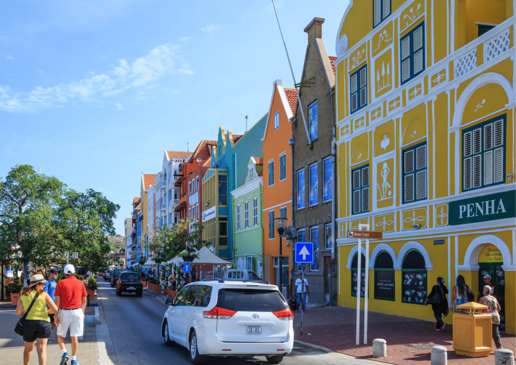 Vehicles driving through colorful downtown Willemstad.