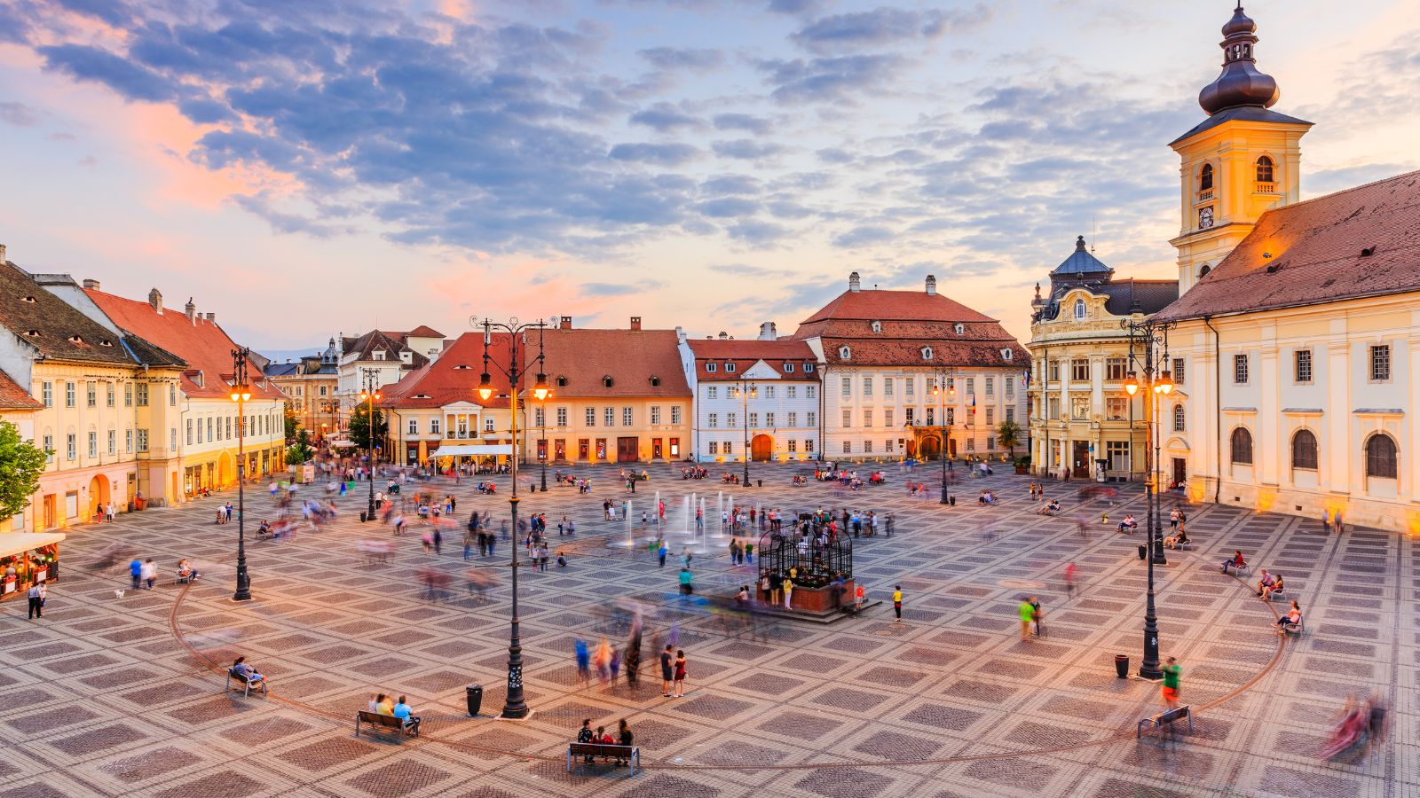 A charming town square known as The Large Square in Romania, Sibiu is bustling with people at sunset.