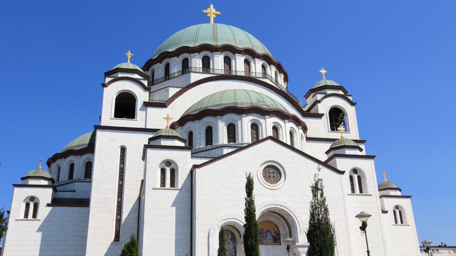 The Temple of Saint Sava in Belgrade, Serbia -- a looming white stone building against a clear blue sky.