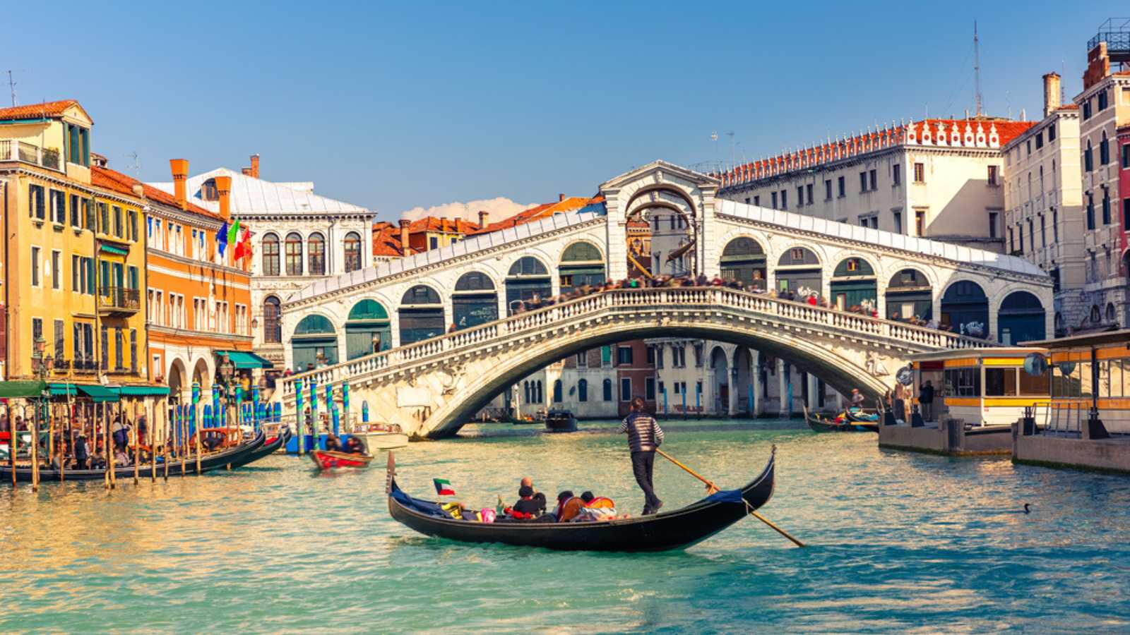 A gondola floats towards Rialto Bridge in Venice, Italy. Gondola rides are common tourist attractions in this popular city.