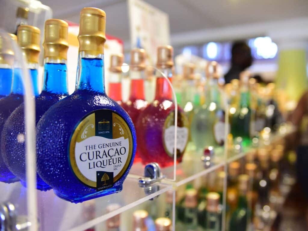 A display of bottles of Curacao liquor in a glass display case.