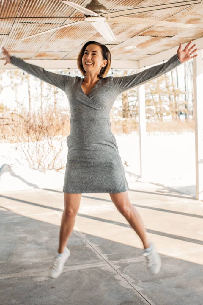 Showing the Daphne dress in a jumping pose with white sneakers