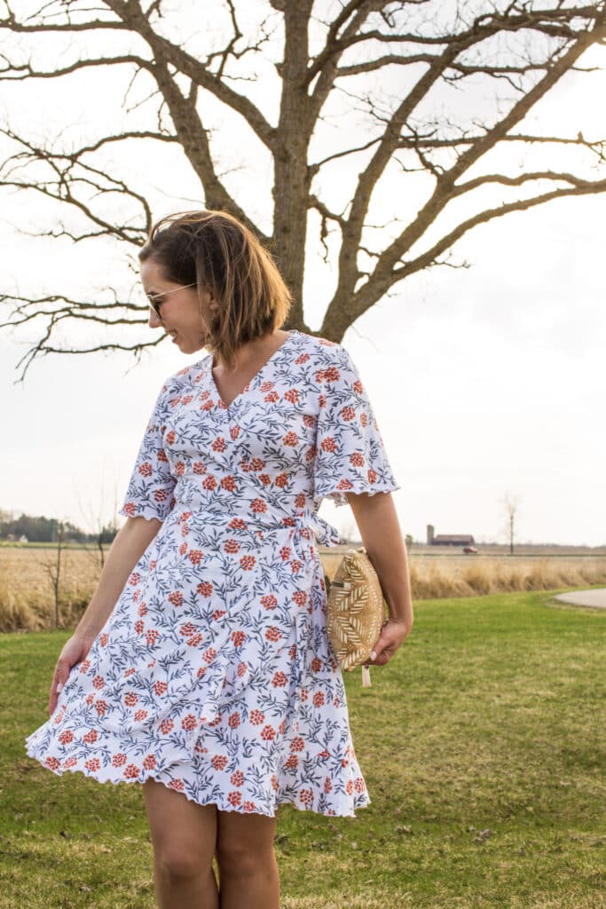 Lindsey of Have Clothes, Will Travel wearing a floral Passion Lilie summer wrap dress with a field and stream as a backdrop