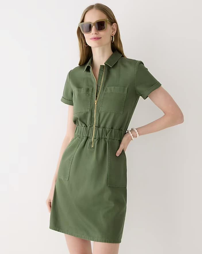 Woman wearing sunglasses and a green dress from J crew, posing with her hand on her hip
