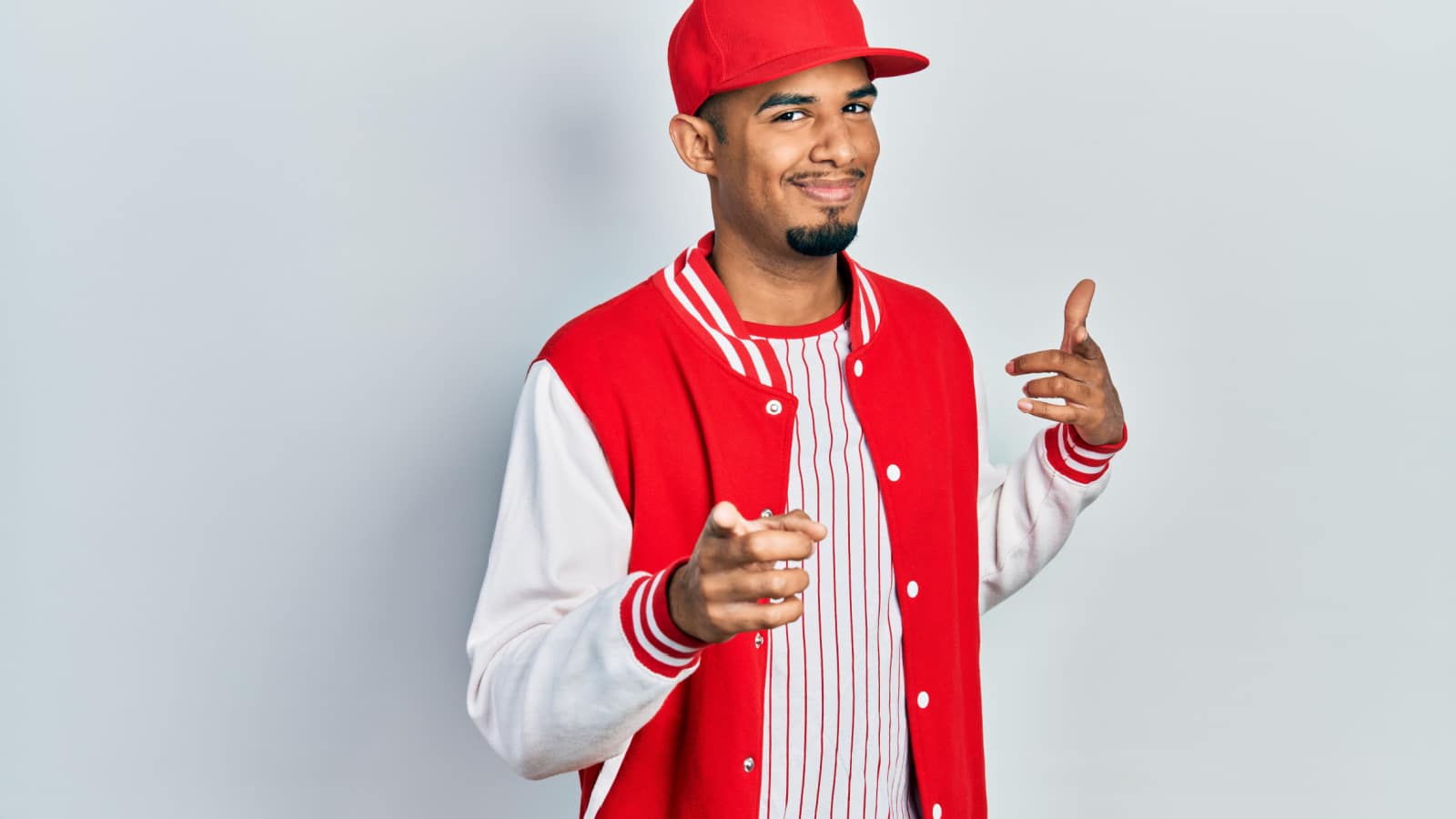 Young african american man wearing baseball uniform pointing fingers to camera with happy and funny face. good energy and vibes.