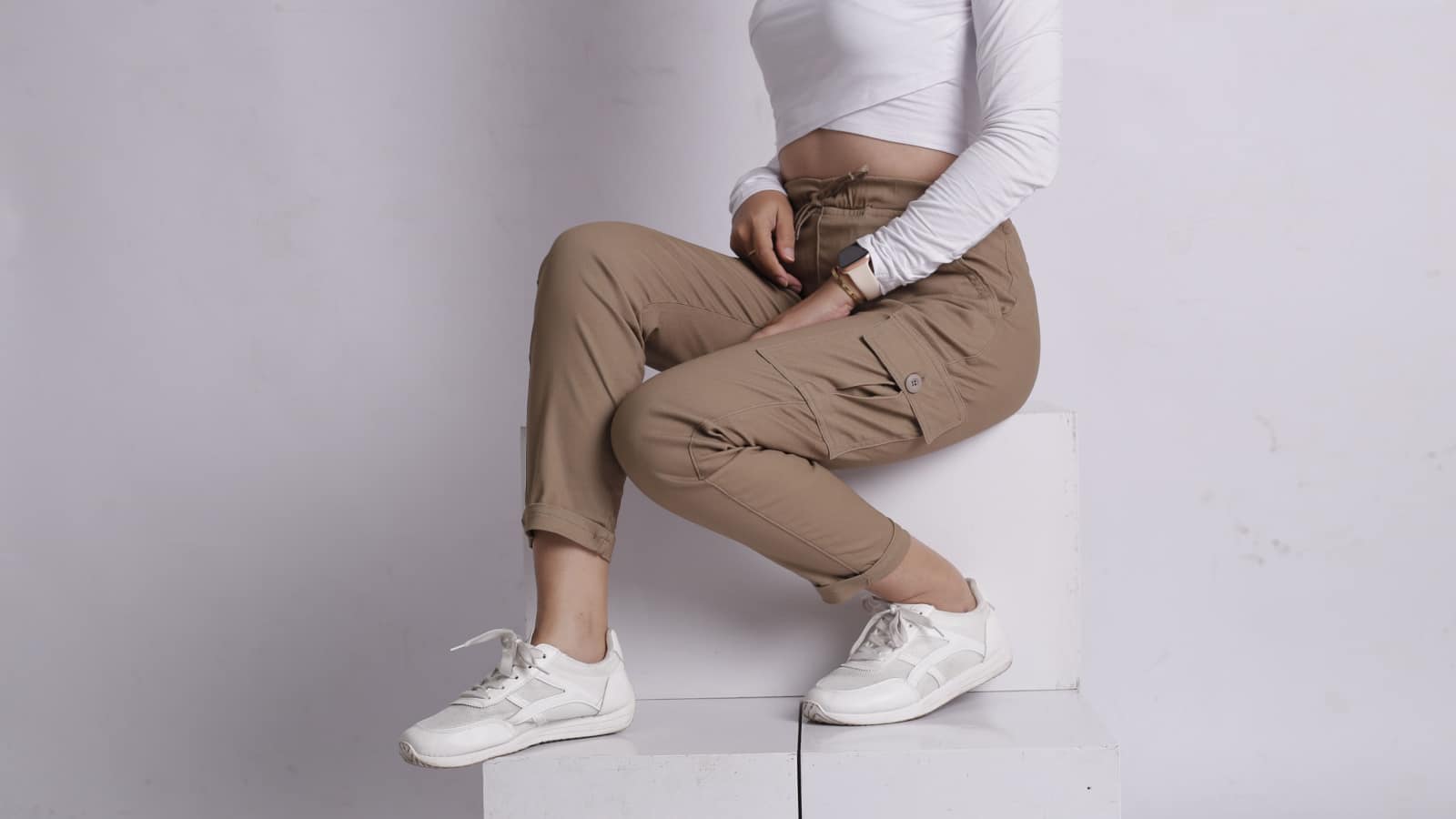 woman wearing white shirt and beige pants taking a photo in the studio