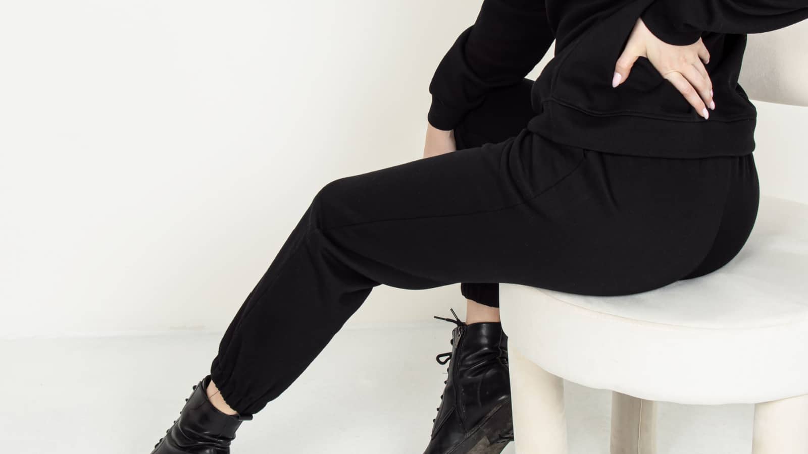 Woman in black tracksuit. Square. Women's tracksuit with joggers made of thick fabric. Autumn boots