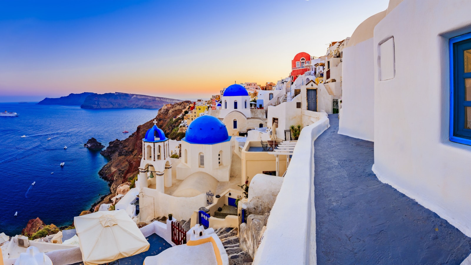 Amazing sunset view with white houses in Oia village on Santorini island in Greece.