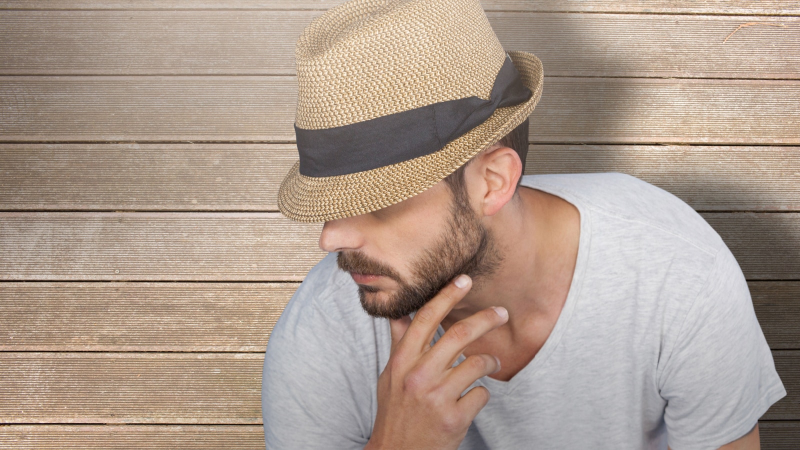 Handsome man wearing hat against wooden surface with planks