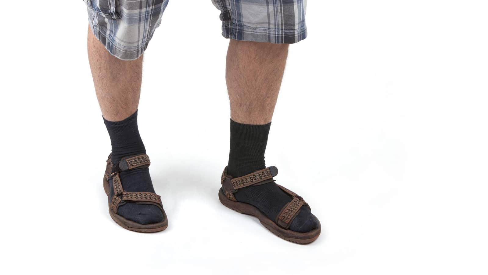 Beauty: studio shot of a man wearing sandals with socks and having hairy legs, isolated on white.