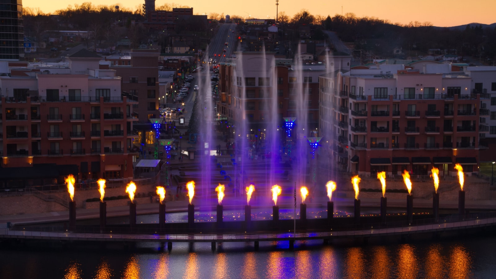 Skyline view of Branson, Missouri with the display showing at the landing waterfront park area. The fountain has fire reflection into the water with tourist watching as they shop.