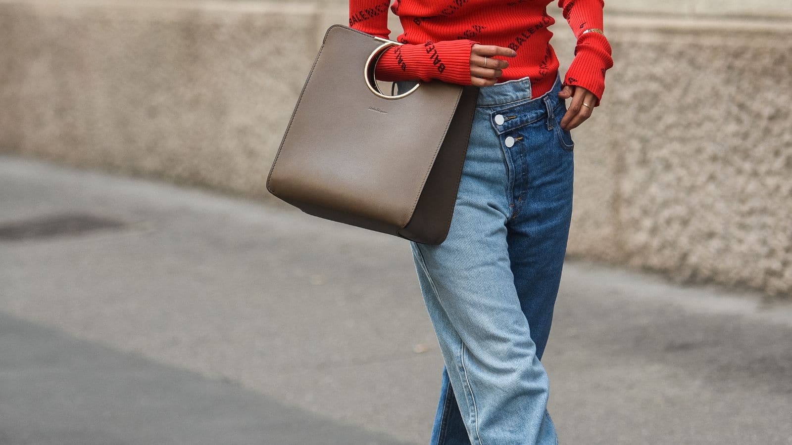 Milan, Italy - September 22, 2018: Fashionable woman wearing blue jeans and red Balenciega sweater on the streets of Milan, detail.