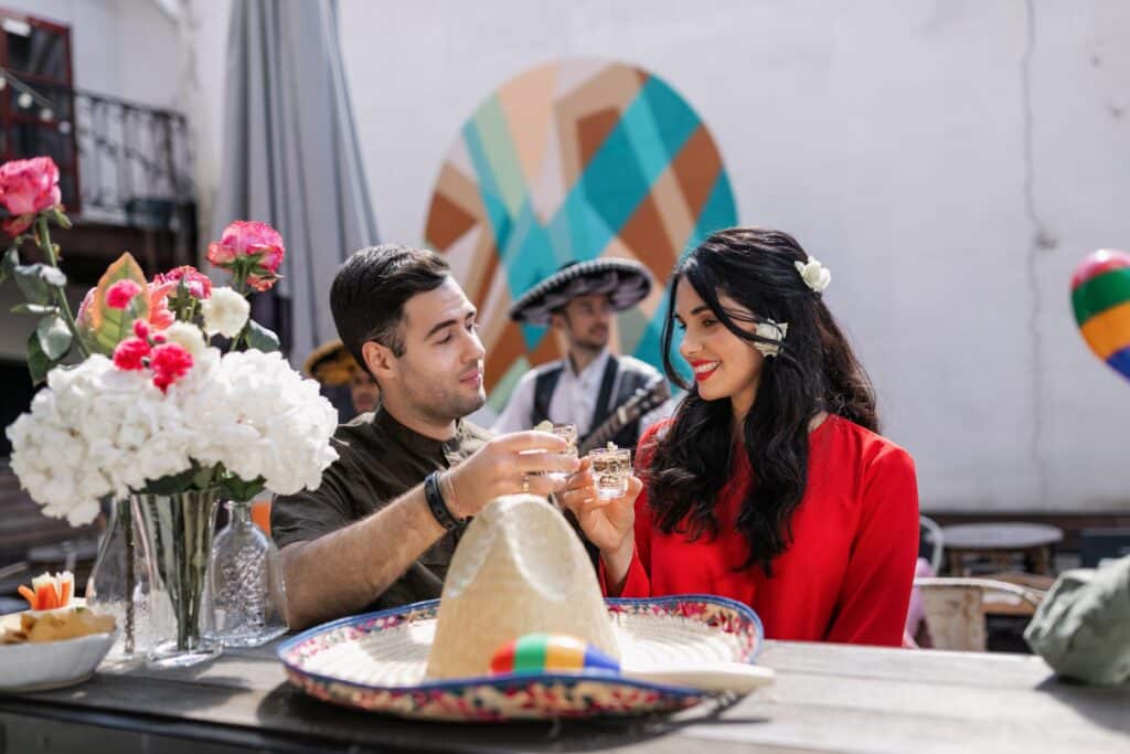 Couple toasting a shot with a sombrero on the table for Cinco de Mayo