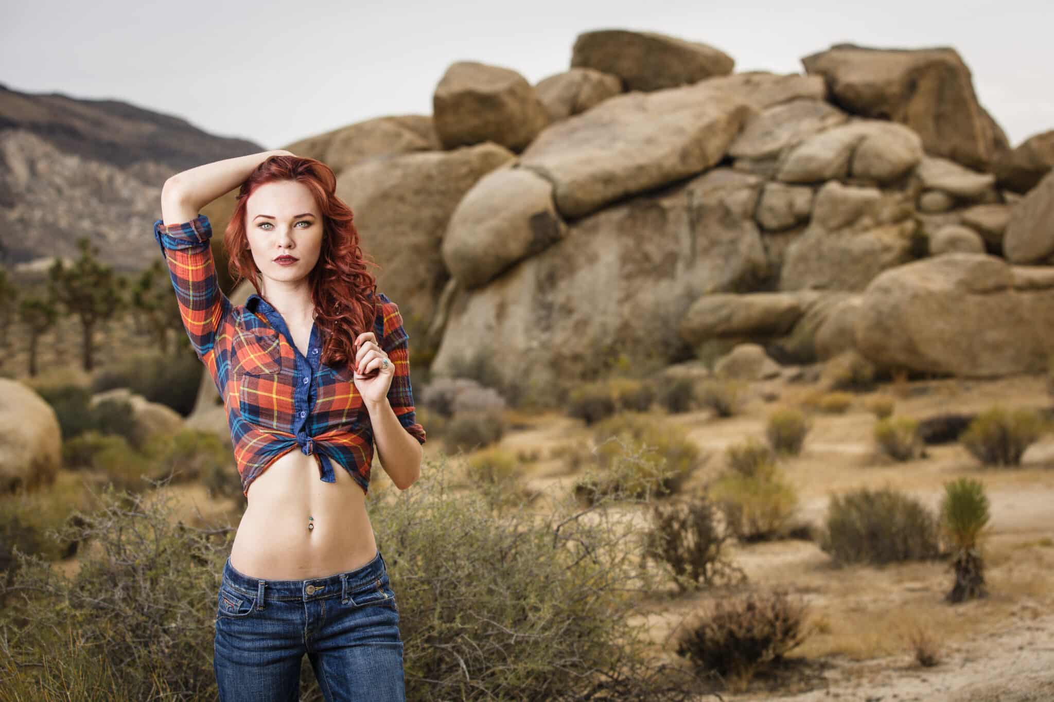 Young model wearing red plaid shirt and low-rise jeans posing at Joshua Tree National Park