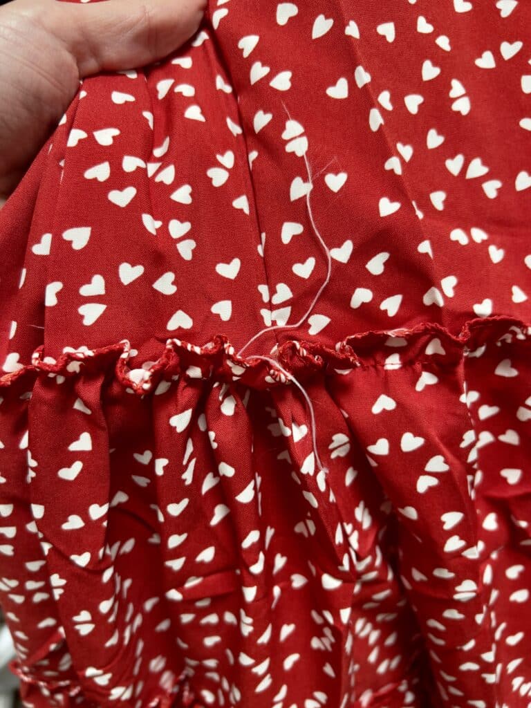 Red Temu dress with white hearts showing poor stitching and loose threads