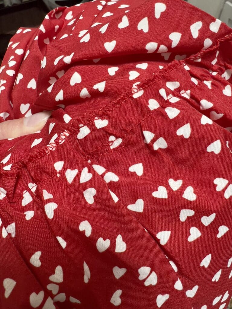 Red Temu dress with white hearts showing poor stitching and loose threads
