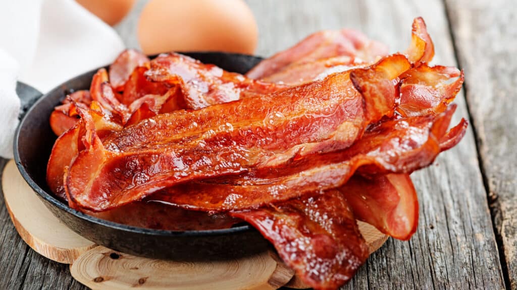 Hot fried bacon pieces in a cast iron skillet.