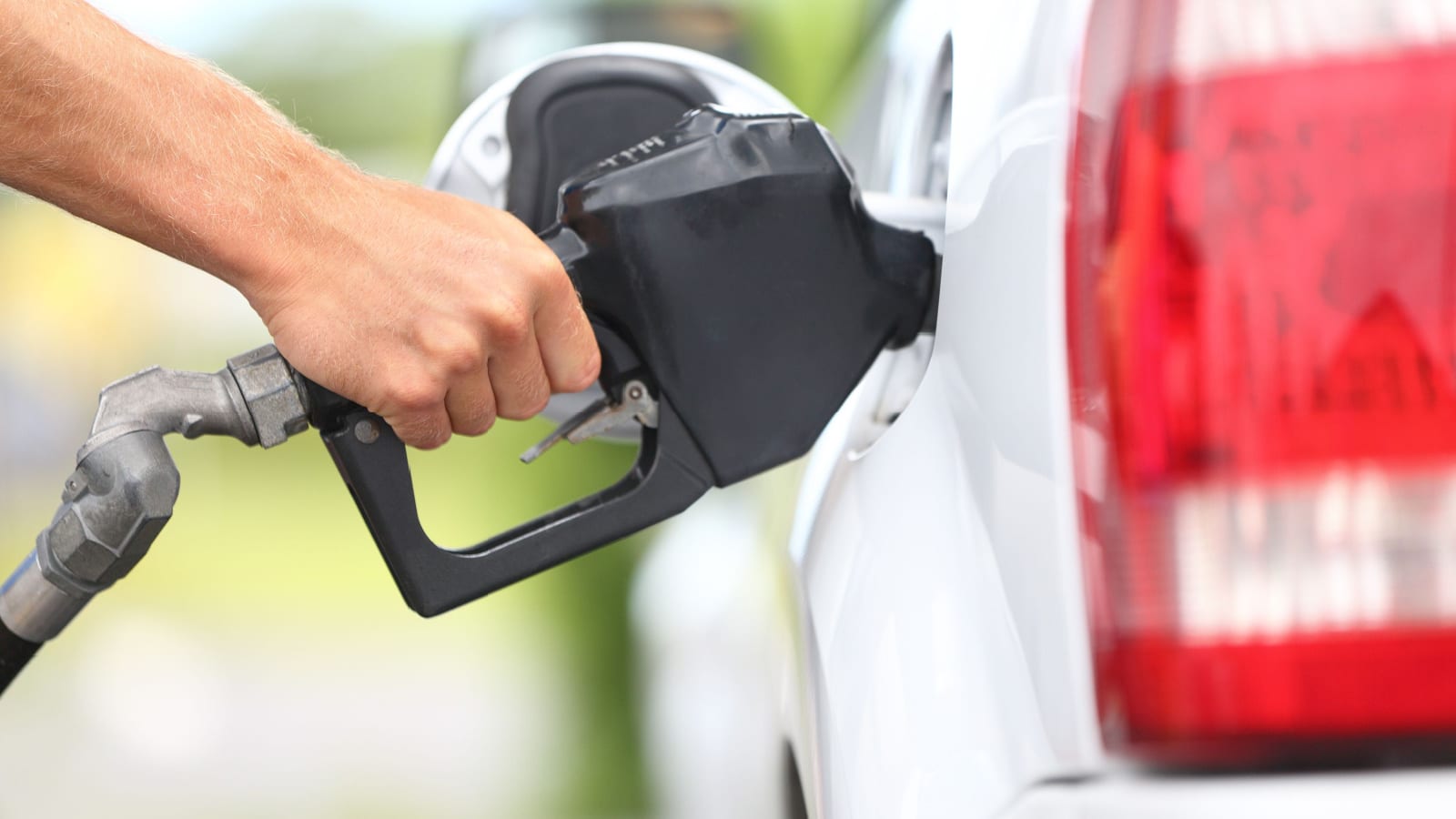 Pumping gas at gas pump. Closeup of man pumping gasoline fuel in car at gas station.