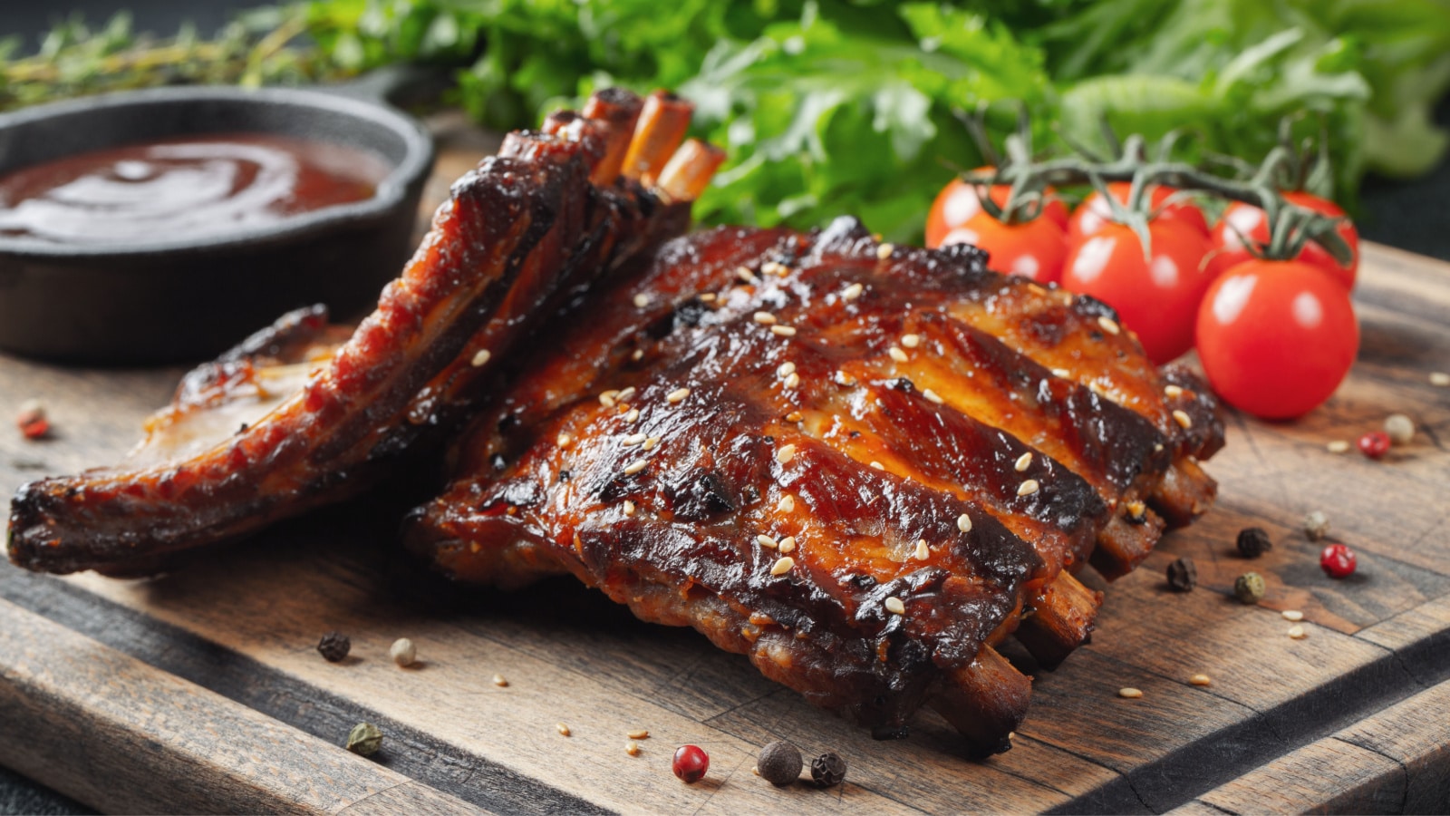 Closeup of pork ribs grilled with BBQ sauce and caramelized in honey. Tasty snack to beer on a wooden Board for filing on dark concrete background
