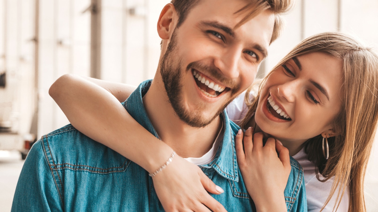 Portrait of smiling beautiful girl and her handsome boyfriend. Woman in casual summer jeans clothes. Happy cheerful family. Female having fun on the street background